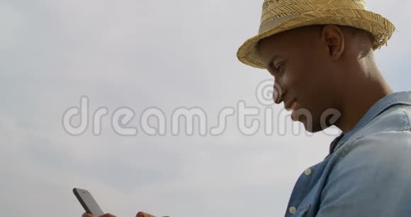海滩上使用手机的非裔美国人的侧视图4k视频的预览图
