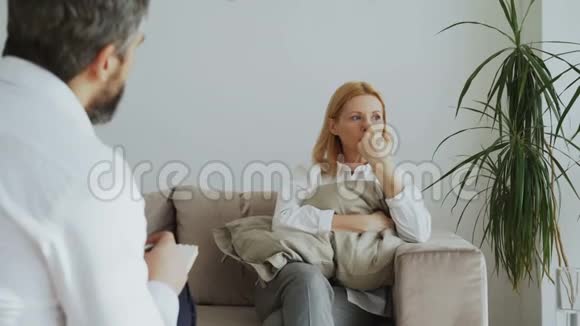 心烦意乱的成年女性抱着枕头在办公室里谈论她与男性精神分析师的问题视频的预览图