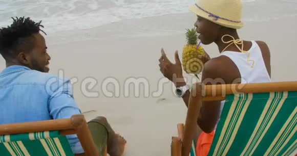 非洲裔美国夫妇在沙滩上喝菠萝汁4k的后视图视频的预览图