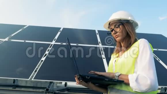 太阳能建筑公司和一名年轻女工拿着笔记本电脑走在那里绿色能源概念视频的预览图