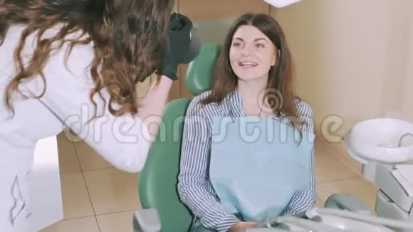 牙医办公室里一个漂亮迷人的年轻女孩正灿烂地微笑着展示着牙医的成果视频的预览图