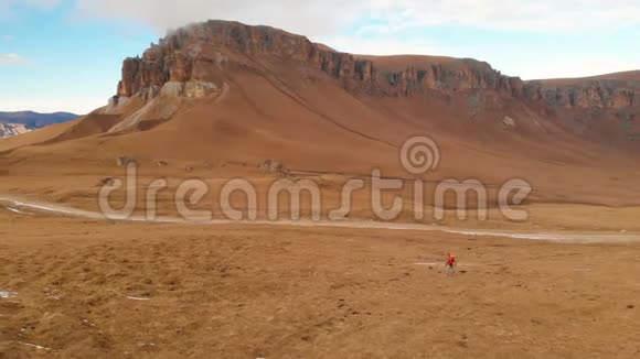 空中景色一个旅行女孩脖子上戴着相机正沿着山坡走着一片群山和一个背景视频的预览图