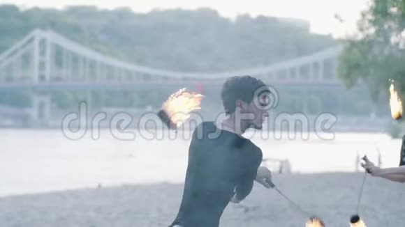 一名男子在树前的河岸上用消防风扇表演能工巧匠视频的预览图