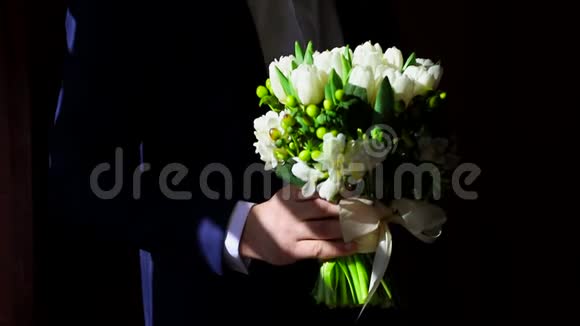 男人的手拿着一束白色郁金香阳光照射在一束白色的郁金香上送给新娘的礼物视频的预览图