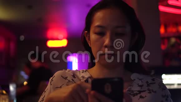 亚洲女人用红色霓虹灯现代夜总会的智能手机视频的预览图