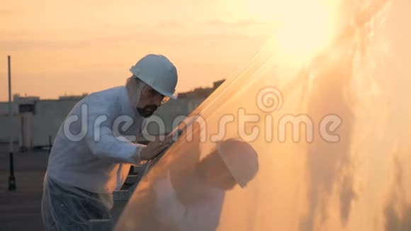 一位男性专家正在擦拭太阳能建筑的阳光表面环保能源理念视频的预览图