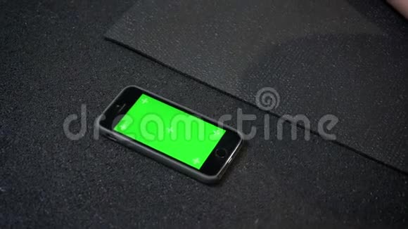 在健身房的karrimat附近有一部彩色绿色屏幕的智能手机视频的预览图