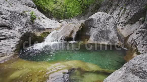 在布满青苔的石质河床中流动的小山河瀑布的正面视图视频的预览图