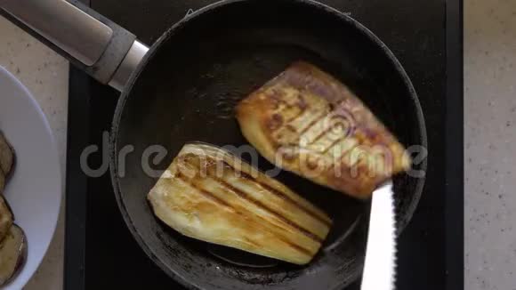 茄子切片用黄油在煎锅里煎女性用刀将手翻过来特写顶部视频的预览图