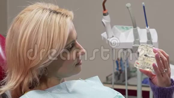 成熟的女人对着镜头微笑拿着牙模在诊所视频的预览图