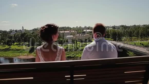 两个情人坐在美丽而高高的河岸上的长凳上轻轻地亲吻着嘴唇视频的预览图