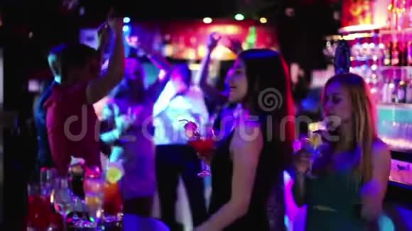 在俱乐部里年轻的学生们在聚会上喝着鸡尾酒跳舞视频的预览图
