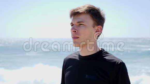 年轻帅哥站在沙滩上跑步锻炼前戴上耳机慢动作视频的预览图