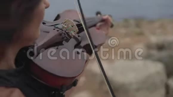 穿黑色连衣裙的年轻小提琴手在海边演奏有小提琴的美女视频的预览图