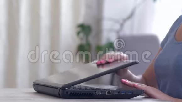 女性用手打开笔记本电脑在键盘上键入文字然后关闭坐在工作场所的电脑视频的预览图