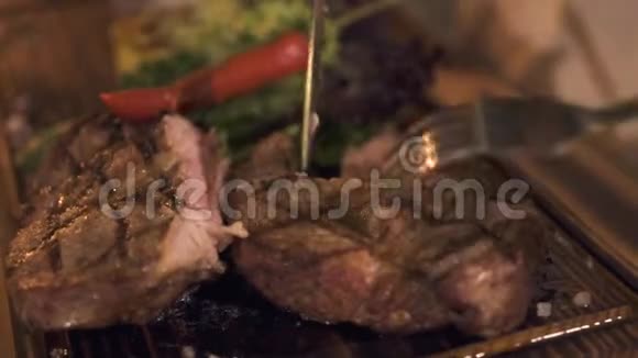 晚餐在烧烤餐厅时男性用刀叉手切烤肉牛排男人切肉烧烤视频的预览图