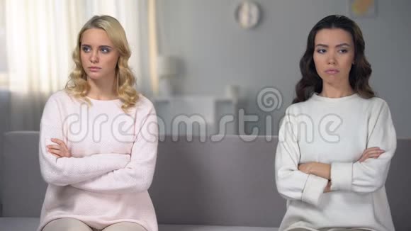两个被冒犯的妹妹坐在沙发的不同侧面在家里吵架视频的预览图