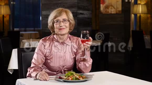 70多岁的有魅力的高级女性坐在一家餐馆里手里拿着一杯水果饮料微笑和快乐视频的预览图