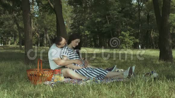 英俊的男人抚摸他怀孕的妻子的腹部视频的预览图