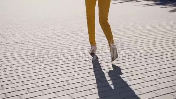 从背后看一个成功的年轻商务女性走在城市街道上在阳光明媚的日子里打电话视频的预览图