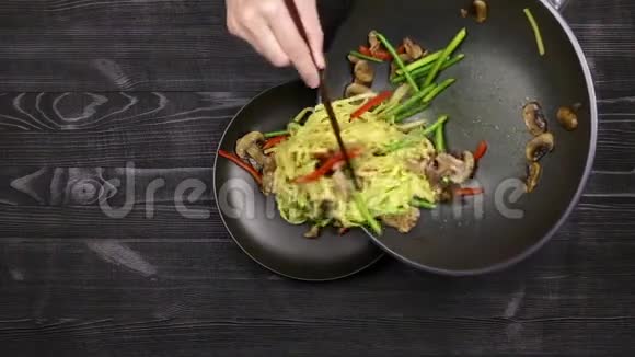 用蒜芽炒面条和切碎的蘑菇片鸡肉放在盘子里用炒锅炒厨师视频的预览图