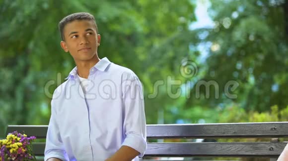 微笑混合种族的少年男孩呈现心爱的女孩花第一次约会在公园视频的预览图