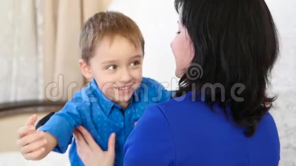 幸福的家庭快乐的孩子在家里抱着他的妈妈在白色沙发上视频的预览图