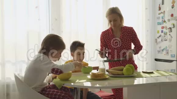 妈妈给两个男孩煎煎饼男孩们正在吃早餐视频的预览图