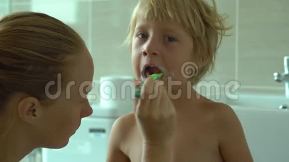 年轻女子在浴室里给她的小儿子刷牙视频的预览图