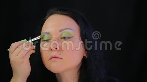 黑发女人把多汁的绿色闪光涂在眼皮上视频的预览图