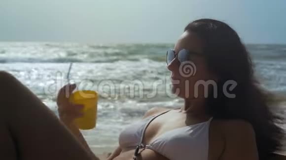 特写镜头戴着墨镜的美女在海边喝着鸡尾酒视频的预览图