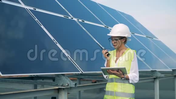 在太阳能建筑附近用对讲机交流的女工程师替代能源概念视频的预览图