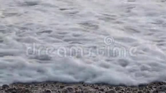 海浪鹅卵石上有很多泡沫视频的预览图