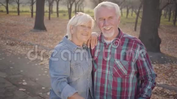 微笑的高加索族夫妇站在阳光下户外聊天退休的成熟家庭在秋日晚上视频的预览图