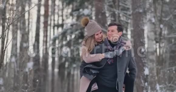 一个年轻的男人和一个穿着外套的女人正在冬天的森林里玩雪动作很慢幸福和幸福视频的预览图