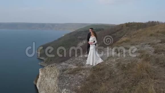 新婚夫妇站在悬崖旁俯瞰大海视频的预览图