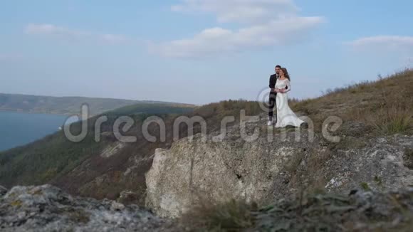 新婚夫妇站在悬崖旁俯瞰大海视频的预览图