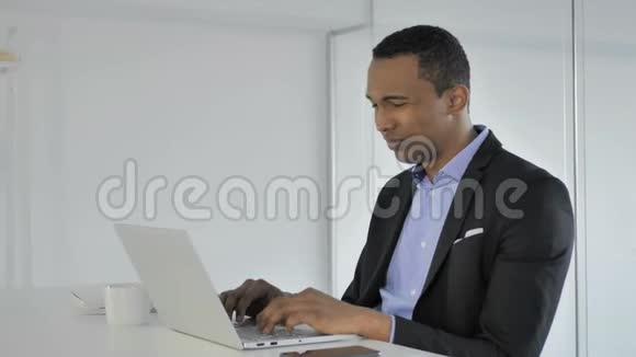 头痛压力大在笔记本电脑上工作的非裔美国商人视频的预览图