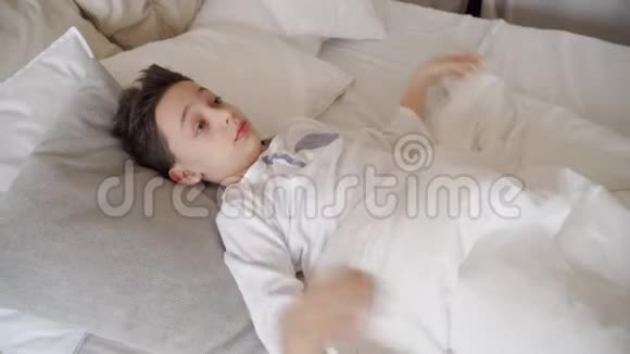 可爱的少年早上醒来在床上伸展身体的男孩视频的预览图
