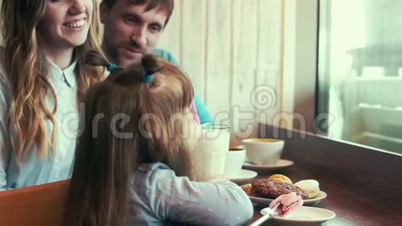 家人在咖啡馆女儿喝奶昔爸爸妈妈交流视频的预览图