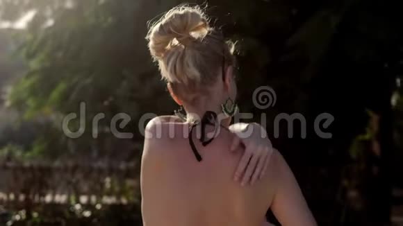 女人的身体油穿比基尼的年轻女人给她的身体涂上奶油绿树树背景视频的预览图