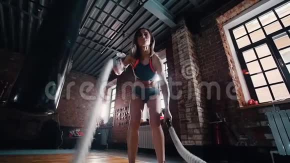在健身房做交叉运动的女人用绳子打地板训练她的手视频的预览图