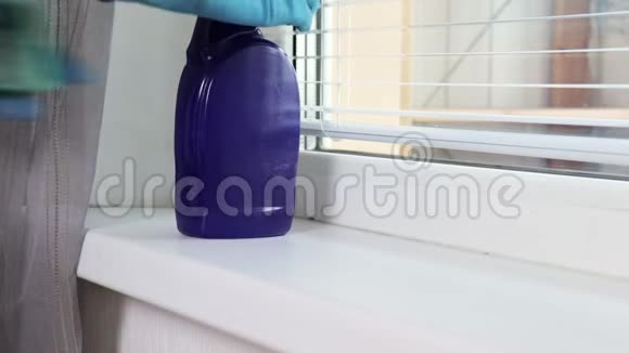 一个女人用蓝色橡胶手套用卫生喷雾和海绵清洗窗台视频的预览图
