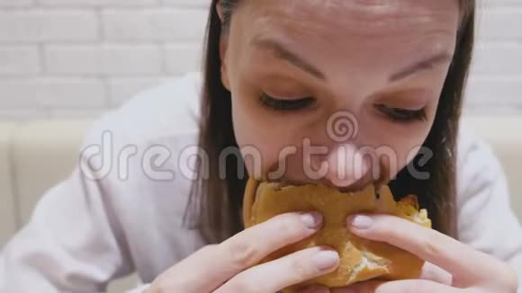 女人在咖啡馆里津津有味地吃着汉堡包特写的脸视频的预览图