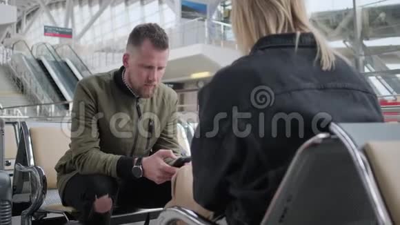 男人和女人在机场使用智能手机视频的预览图