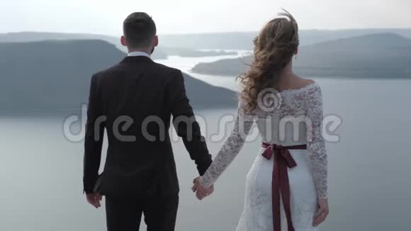 一对神奇而神秘的夫妇从悬崖上眺望海岸视频的预览图