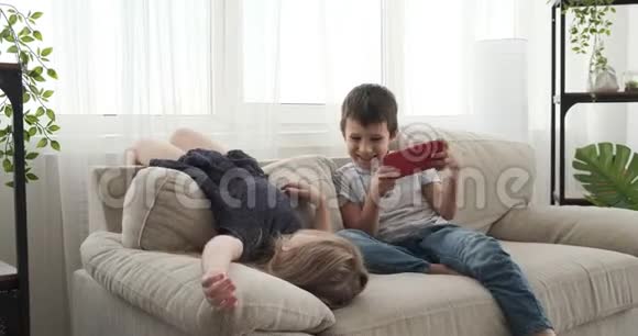 儿童在沙发上玩手机视频的预览图