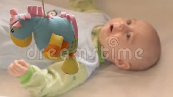 新生婴儿躺在床上看着玩具视频的预览图