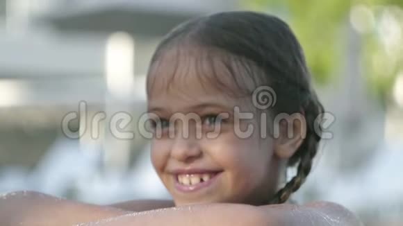 快乐的滑稽女孩戴着黄色太阳镜微笑着看着镜头望着游泳池外抓住边缘视频的预览图