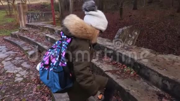 公园里潮湿的石阶上背着背包的小女孩视频的预览图